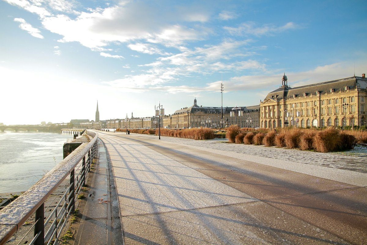 Promenade des quais de Bordeaux sous la lumière du matin, la place de la Bourse au loin
