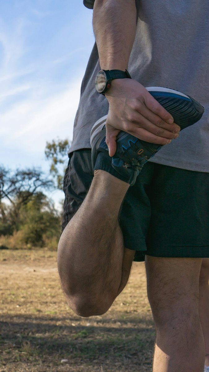 Gros plan d'un coureur qui étire l'avant de sa cuisse après une sortie